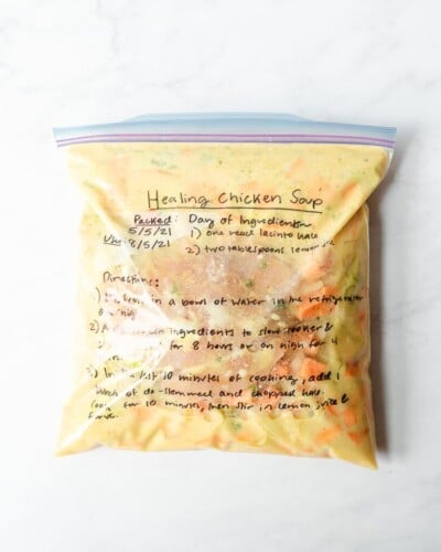 freezer meal healing chicken soup in a labeled ziplock bag on a marble surface