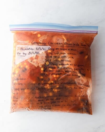 freezer meal creamy chicken enchilada soup in a labeled ziplock bag on a marble surface