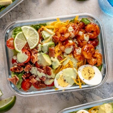 A glass meal prep container filled with spicy shrimp cobb salad.
